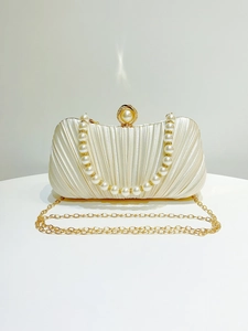 Detailed view of white pleated satin evening bag with pearl clasp and golden chain strap