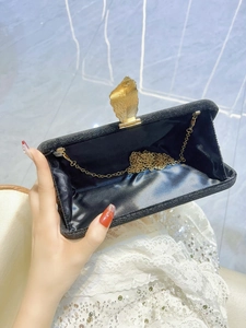 Elegant black shimmer velvet clutch with golden leaf clasp and chain strap for evening events