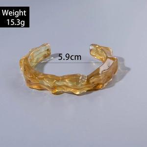 Detailed view of amber resin cuff bracelet showing irregular wavy texture and dimensions