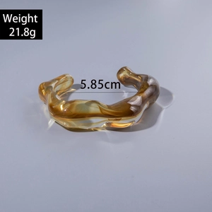Detail of amber acrylic bracelet with irregular wavy texture and 5.85cm diameter