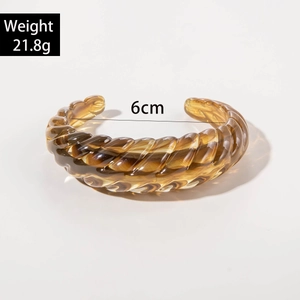 Macro detail of amber brown acrylic cuff featuring irregular twisted ripple texture and size