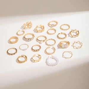 Gros plan d'un lot de 22 bagues dorées avec perles, strass et motifs papillons évidés
