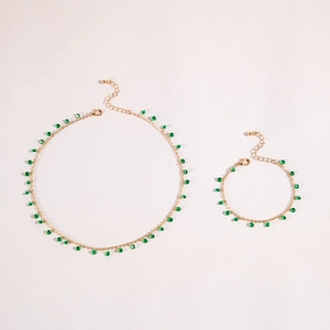 Detailed shot of golden necklace and bracelet set with green eye charms and tassels