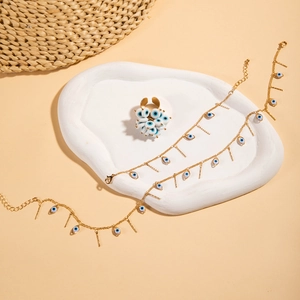 Flat lay of gold Evil Eye jewelry set with heart ring and layered tassel necklaces