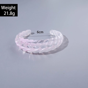 Macro detail of clear acrylic open bangle with twisted texture and pink gradient