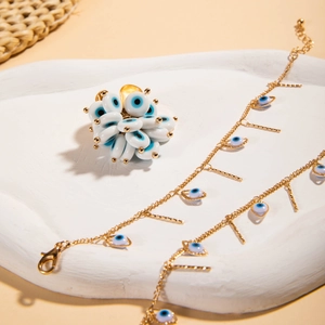 Detail of evil eye jewelry set with gold tassel bracelet and heart ring on stone tray