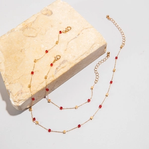 Detail of gold evil eye necklace with red charms on natural stone display