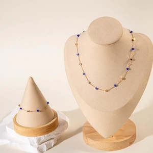 Detail of gold necklace and bracelet set with blue cube beads on a display stand