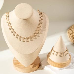 Detailed view of a gold fringed necklace and bracelet set with crystal charms on stands