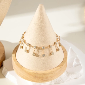 Close-up of gold chain featuring sparkling rhinestones on a minimalist jewelry stand