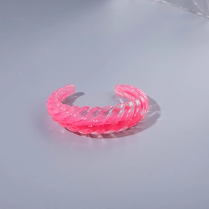 Pink transparent acrylic open bangle featuring a unique spiral texture and geometric design