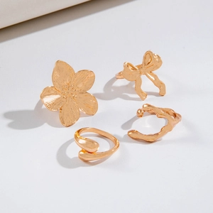 Detailed set of four gold alloy jewelry pieces including flower and bow shaped rings