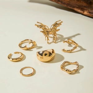 Detail of 7-piece gold alloy ring set featuring molten butterfly and wavy textured bands
