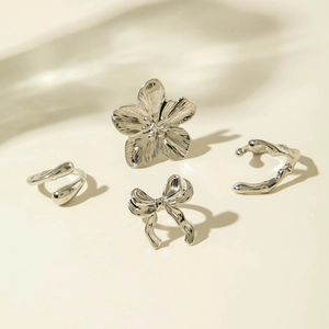 Silver flower and bow ring set with liquid metal style on a neutral background