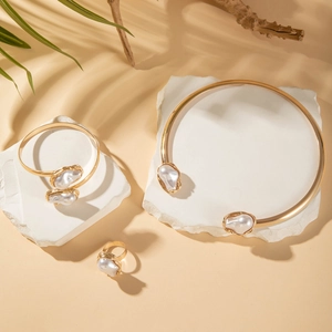 Baroque irregular pearl jewelry set with gold alloy necklace, bracelet, and ring on stone