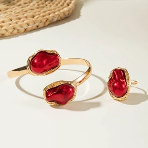 Detailed shot of hammered gold bangle and ring set with red baroque irregular pearls