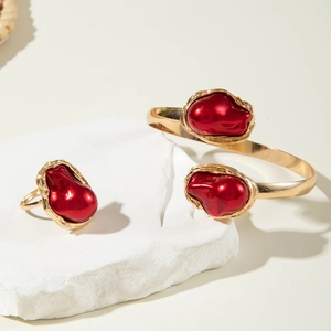 Detailed close-up of Baroque gold bracelet and ring set with large red faux pearls
