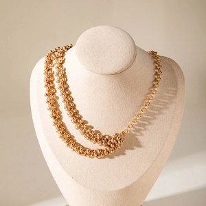 Close-up of golden double-layer necklace featuring beaded strands and circular links