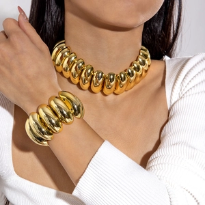 Dettaglio ravvicinato del set collana e bracciale dorato lucido con trama a costine