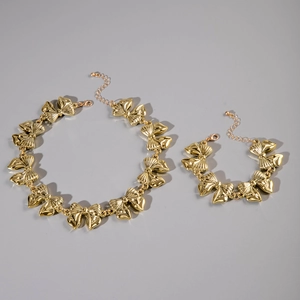 Dettaglio del set collana e bracciale a fiocco dorato con finitura lucida e moschettone