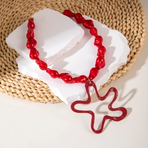 Statement red beaded necklace with large hollow star pendant on minimalist stone display
