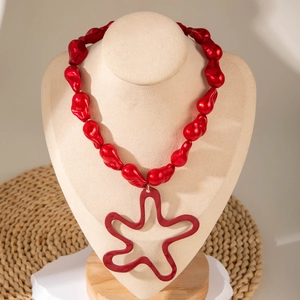 Close-up of red beaded necklace with large hollow wave star pendant on a neck display