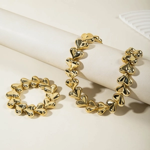 Close-up of polished gold heart link necklace and bracelet set on geometric props