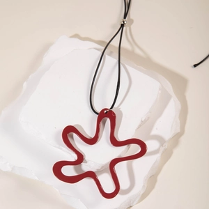 Detailed close-up of a red wavy abstract pendant with an adjustable black cord on stone