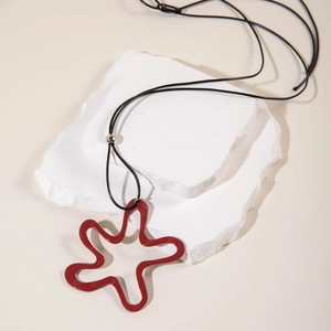 Macro view of burgundy hollow star pendant with glossy finish on a minimalist cord