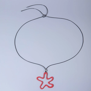 Close-up of a red abstract star pendant on a black cord with an adjustable slider knot