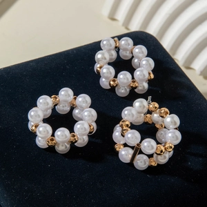 Detailed view of elegant pearl and gold bead stack rings on black velvet stand