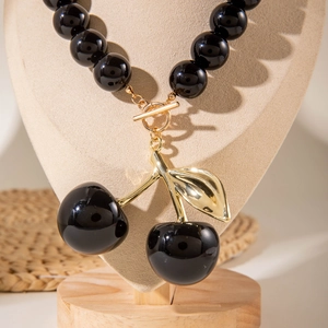 Detail of acrylic cherry pendant necklace with black beads and gold T-bar toggle clasp