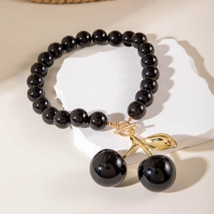 Detail view of black acrylic beaded necklace with cherry pendant and golden OT clasp