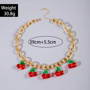 Detailed view of chunky gold chain necklace with red cherry pendants and lobster clasp