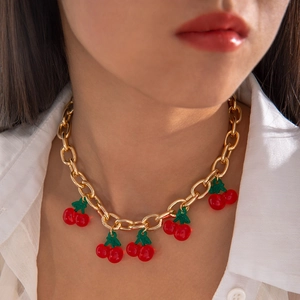 Close-up of gold chunky link necklace with translucent red resin cherry pendants