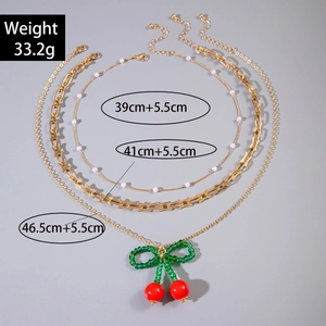 Detailed specs of 3-layer gold chain necklace with cherry pendant and bow clasp