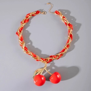Detail of red acrylic cherry pendant on gold chain with red silk ribbon intertwining