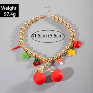 Detail view of gold bead necklace with red cherry, mushroom, and heart pendants