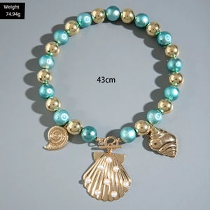 Detail of nautical beaded necklace featuring golden seashell charms and blue pearls