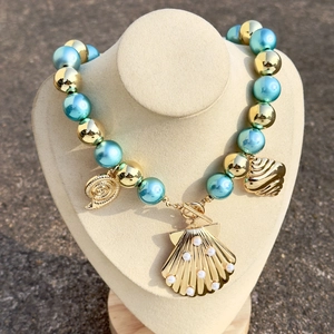 Detail of beaded sea theme necklace with gold scallop shell pendant and OT toggle clasp