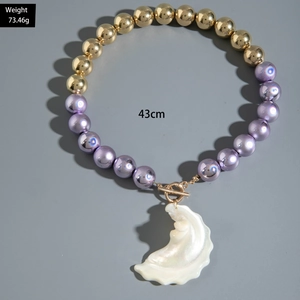 Detail of beaded necklace with gold and purple beads and large iridescent pearl pendant