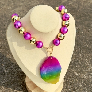 Rainbow gradient pendant necklace with pink metallic beads on jewelry mannequin