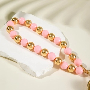 Detail of beaded strap featuring pink and gold metallic beads on a textured stone