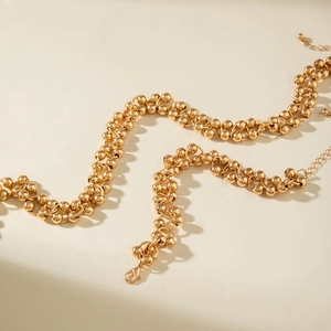 Close-up of double-layered gold bead chain necklace with lobster clasp and extension