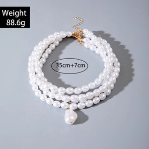 Dettaglio della collana di perle a più strati con pendente barocco e chiusura dorata