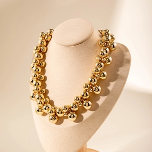 Close-up of layered chunky gold bead choker necklace on a display stand with high polish
