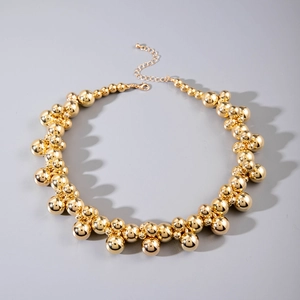 Detail of chunky gold bead necklace with polished metallic spheres and lobster clasp closure