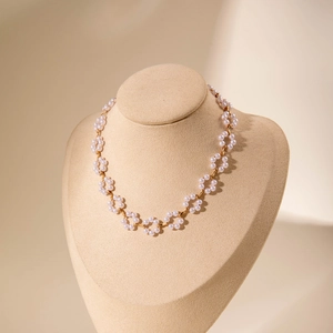 Detail of beaded floral necklace featuring white pearls and gold flower links