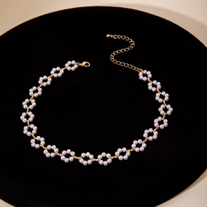 Close-up of pearl flower cluster necklace on black velvet stand with gold lobster clasp