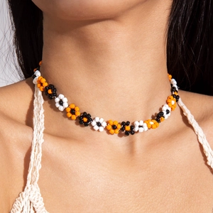 Detailed shot of handmade colorful beaded daisy choker with orange and black floral patterns